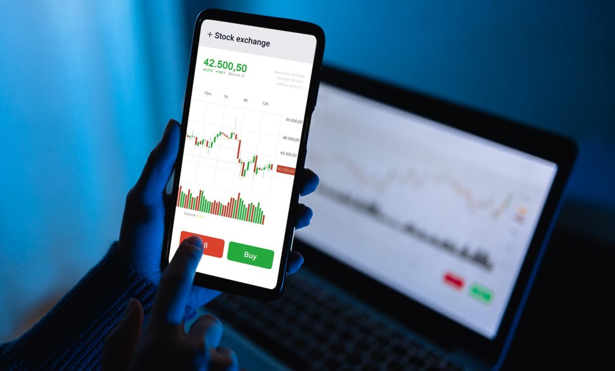 Trader using stock exchange app online for trading operations in mobile phone - Focus on screen phone